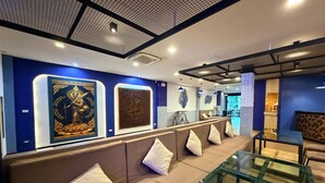 A modern interior with a sofa, glass table, and wall art. - Serene Suite with Balcony and Pool View (Tambon Patong)