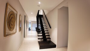Un interior moderno con una escalera espiral, obras de arte enmarcadas en las paredes y un diseño limpio y minimalista.