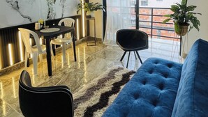 A modern living room with a marble wall, a blue sofa, a dining table with chairs, and a large window with a view. - Luxury Aparment in Chinacota with Studio Perfect for Remote Work (Chinácota)