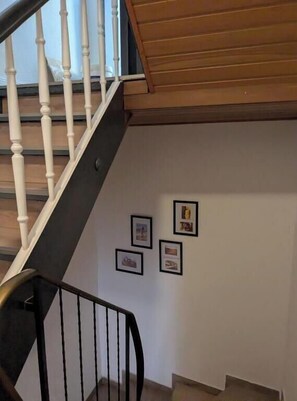 A staircase with white balusters and a wooden handrail, leading to a landing with framed pictures on the wall. - Holiday apartment Kuxborn in our guesthouse in the old town of Zell (Moselle) (Zell (Mosel))