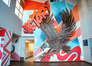 Un mural con un águila y la palabra 'VICTORY' en letras negritas, sobre un fondo geométrico y lleno de color.