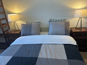 A bed with a checkered bedspread, two bedside tables with lamps, and a wooden ladder. - Rosemary - Cozy and lots of natural light (Porto)