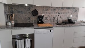 Moderni keittiö, jossa on sisäänrakennettu uuni, astianpesukone ja kahvinkeitin.