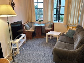 A living room with a TV, a sofa, a small table, and a bench with cushions. - Rosemary - Cozy and lots of natural light (Porto)