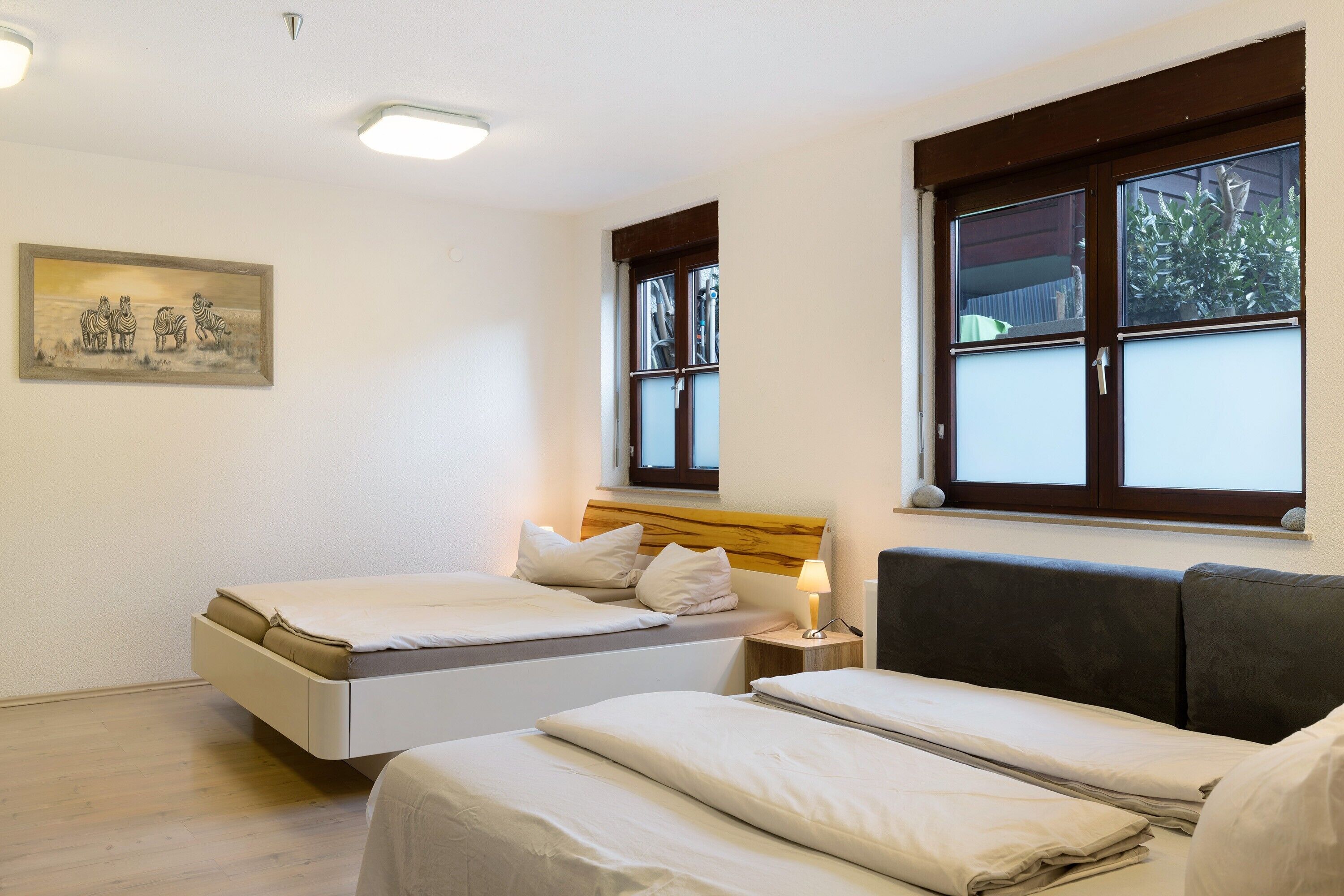 A hotel room with two beds, a painting on the wall, and a window with a view.