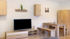A modern living room with a flat-screen TV, wooden cabinets, a bench, and a small table. - Apartment "Citywohnung Tettnang" with Wi-Fi (Tettnang)