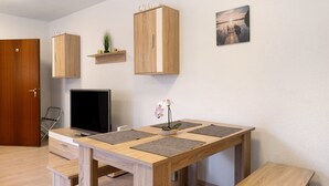 A modern room with a wooden dining table, a TV, and a wooden wardrobe with a 'Welcome' sign. - Apartment "Citywohnung Tettnang" with Wi-Fi (Tettnang)