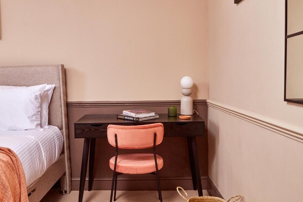 A bedroom with a bed, a desk, a chair, and a lamp.