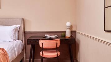 A bedroom with a bed, a desk, a chair, and a lamp.