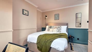 Un dormitorio con cama, mesita de noche, lámpara y espejo en la pared.
