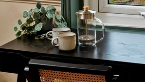 A wooden table with a coffee maker, two mugs, and a potted plant. - Settle Winchester (Winchester)