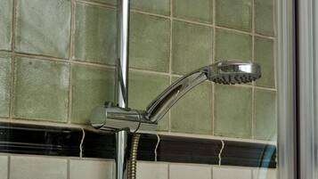 Un cabezal de ducha cromado fijado a una pared con revestimiento de azulejos.