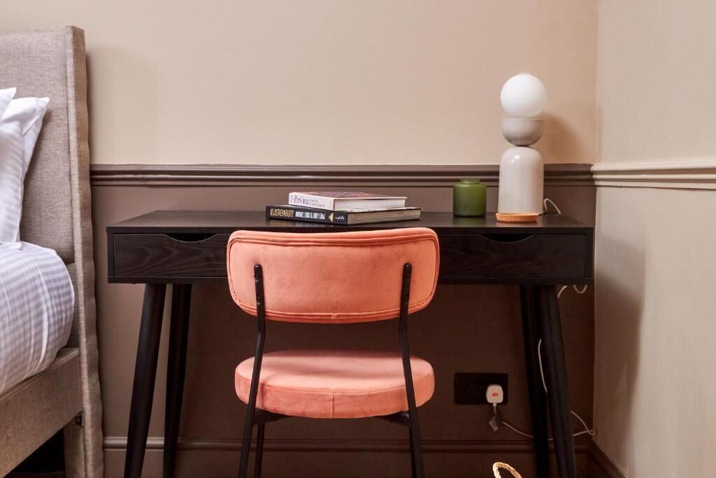 A room with a bed, a desk with a chair, a lamp, and a few books.