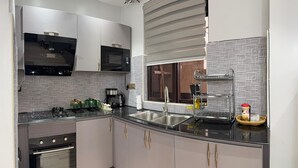 A modern kitchen with a built-in microwave, stove, oven, and a large window with blinds. - Luxurious 1 BR Apt in quaint Kampala with power backup. (Kampala)