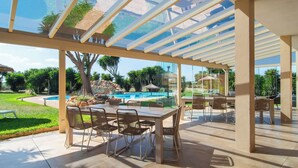 Terrassa exterior amb sostre de vidre, piscina i zona de menjador amb cadires i taula.
