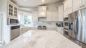 A modern kitchen with white cabinetry, stainless steel appliances, and a marble countertop. - Ski, Hike & Bike: 4,000 Sq Ft Bell Canyon Retreat (Sandy)