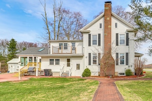 A two-story house with a brick chimney, a front porch, and a small deck.
