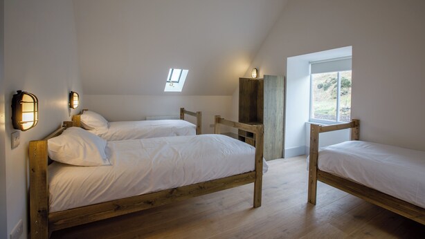 A room with three wooden beds, a skylight, and a window. - Portsoy Sail Loft (Portsoy)
