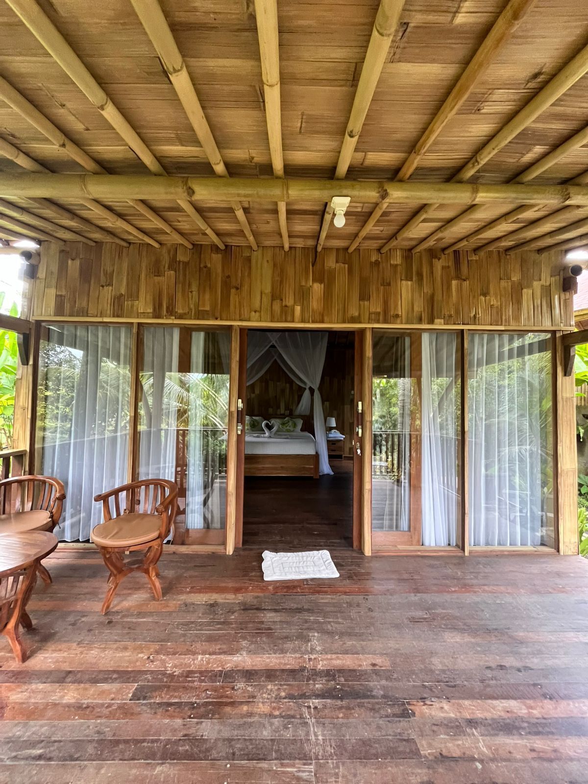 A wooden structure with a bed, curtains, and a table with chairs.