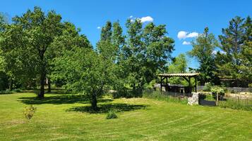 Un parc avec un kiosque, des arbres et un mur de pierre.