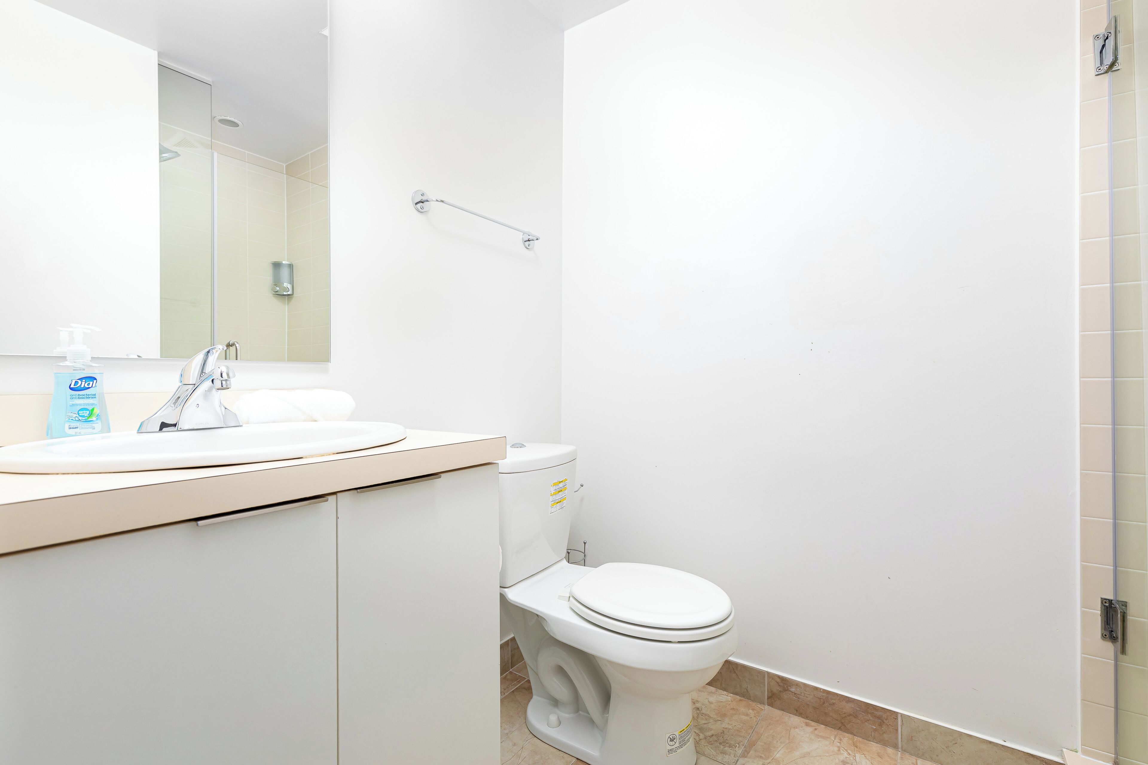 Un baño moderno con lavamanos blanco, inodoro y cabina de ducha de vidrio.