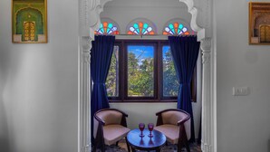 Ein Zimmer mit Fenster, zwei Stühlen und einem Tisch mit zwei Gläsern.