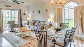 Una amplia sala de estar con un sofá, sillas, una mesa de centro y una mesa de comedor.