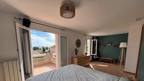 A bedroom with a bed, a dresser, a chair, a lamp, and a view of the outside. - VILLA VUE MER LA FARDELOIE (La Ciotat)
