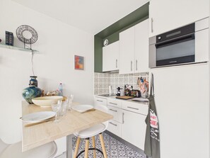 A modern kitchen with white cabinets, a black oven, and a tiled backsplash. - Superb apartment for 2 with sea view (Saint-Gilles-Croix-de-Vie)