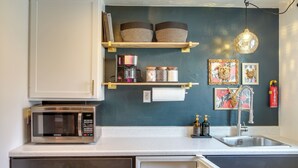 A kitchen with a microwave, shelves with baskets, a coffee maker, jars, and a sink. - Unit 4: Central 1-BR, New Bath, 3 Mi to Dtwn (Spokane)
