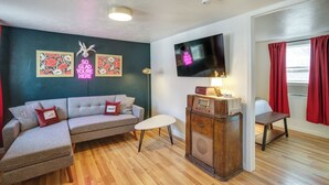 A living room with a sofa, a small table, a vintage radio, and a flat-screen TV mounted on the wall. - Unit 4: Central 1-BR, New Bath, 3 Mi to Dtwn (Spokane)