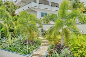 Ein modernes Gebäude mit mehreren Balkonen, umgeben von üppiger tropischer Vegetation und einer zentralen Treppe.