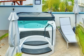Ein Whirlpool mit Stufen, einer Liege und einem Sonnenschirm.