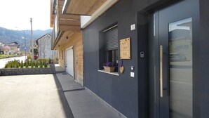 Un edificio con fachada oscura, una puerta de garaje, un ventanal con planta en maceta y un letrero que dice 'CIMUS'.