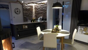 Eine moderne Küche mit einer Wandverkleidung aus Stein, einem runden Esstisch mit Stühlen und einem Fernseher an der Wand.