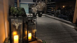 Eine Dachterrasse mit Laternen, Topfpflanzen und einem Geländer.