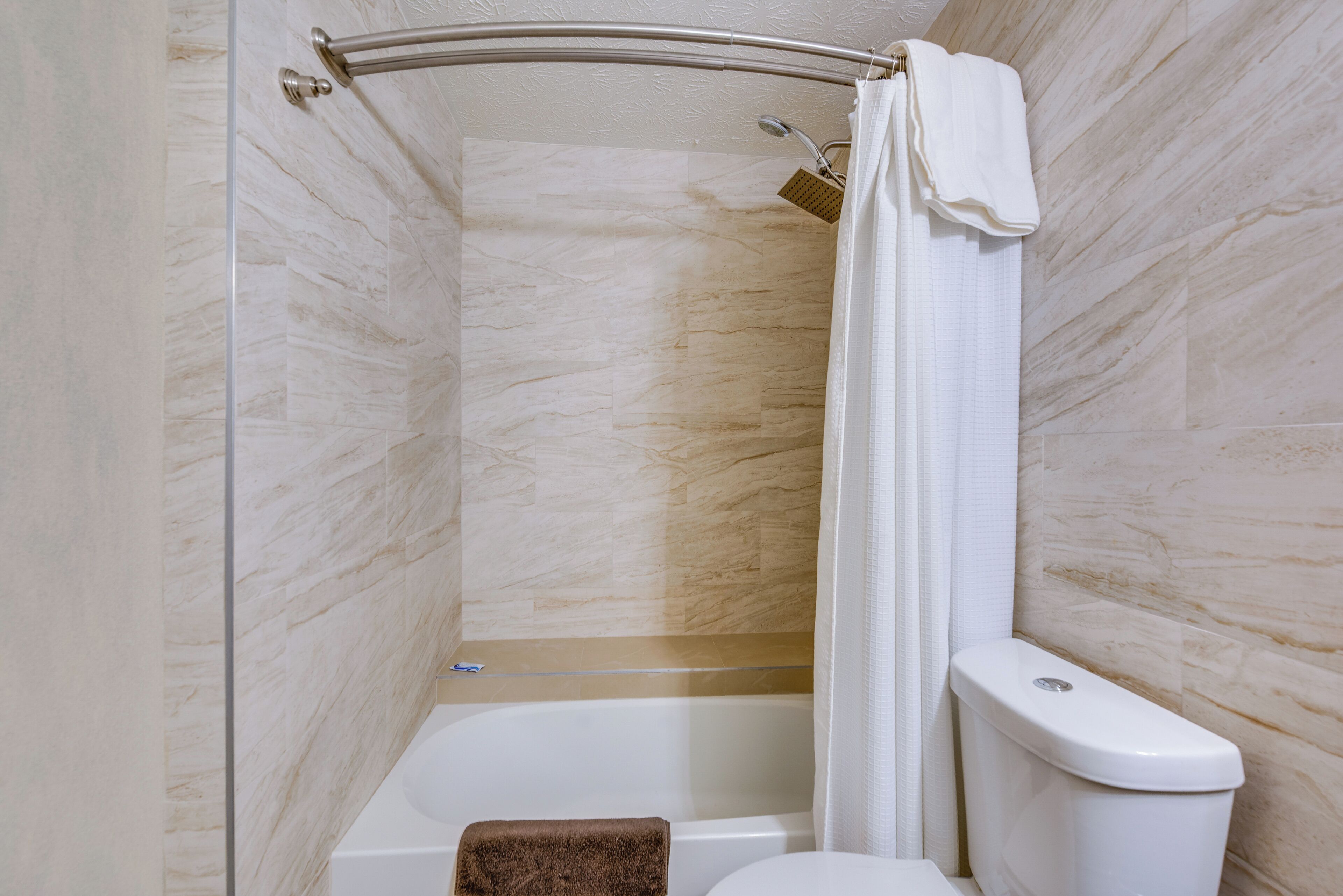 A bathroom with a shower, toilet, and bathtub.