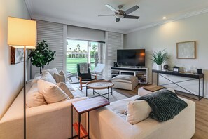 Een woonkamer met een bank, salontafel, televisie en een balkon met uitzicht.