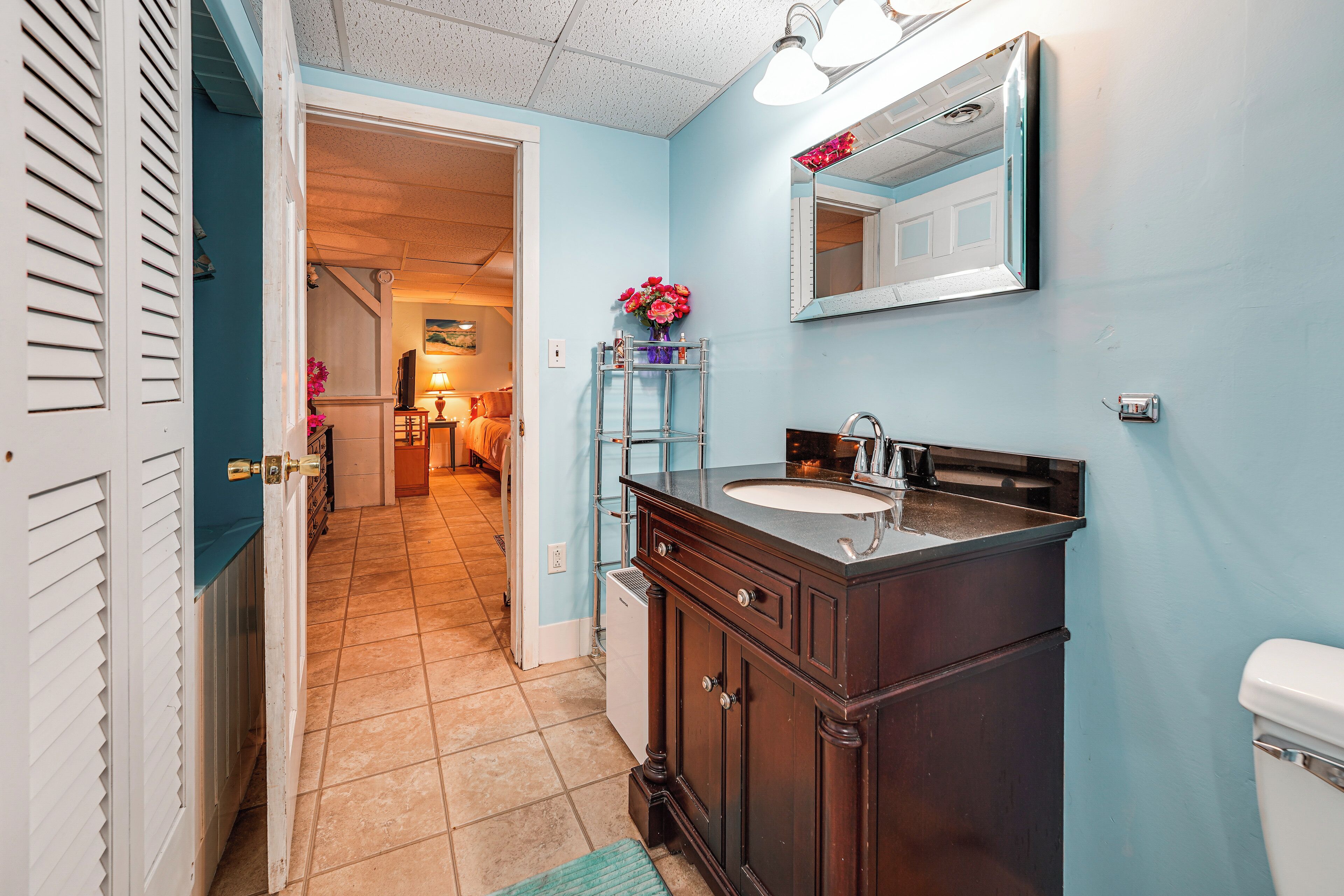 A bathroom with a dark wooden vanity, a white toilet, and a blue wall.
