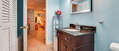 A bathroom with a dark wooden vanity, a white toilet, and a blue wall.