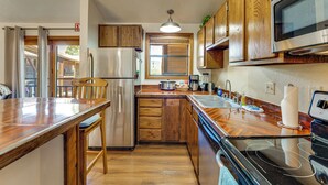 A kitchen with wooden cabinets, a stainless steel refrigerator, a microwave, and a stove. - Steps to the New Angel Express Lift! Fun Condo (Angel Fire)