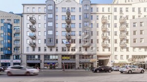 Ein mehrstöckiges Gebäude mit Balkonen, Geschäften und einem Parkplatz.