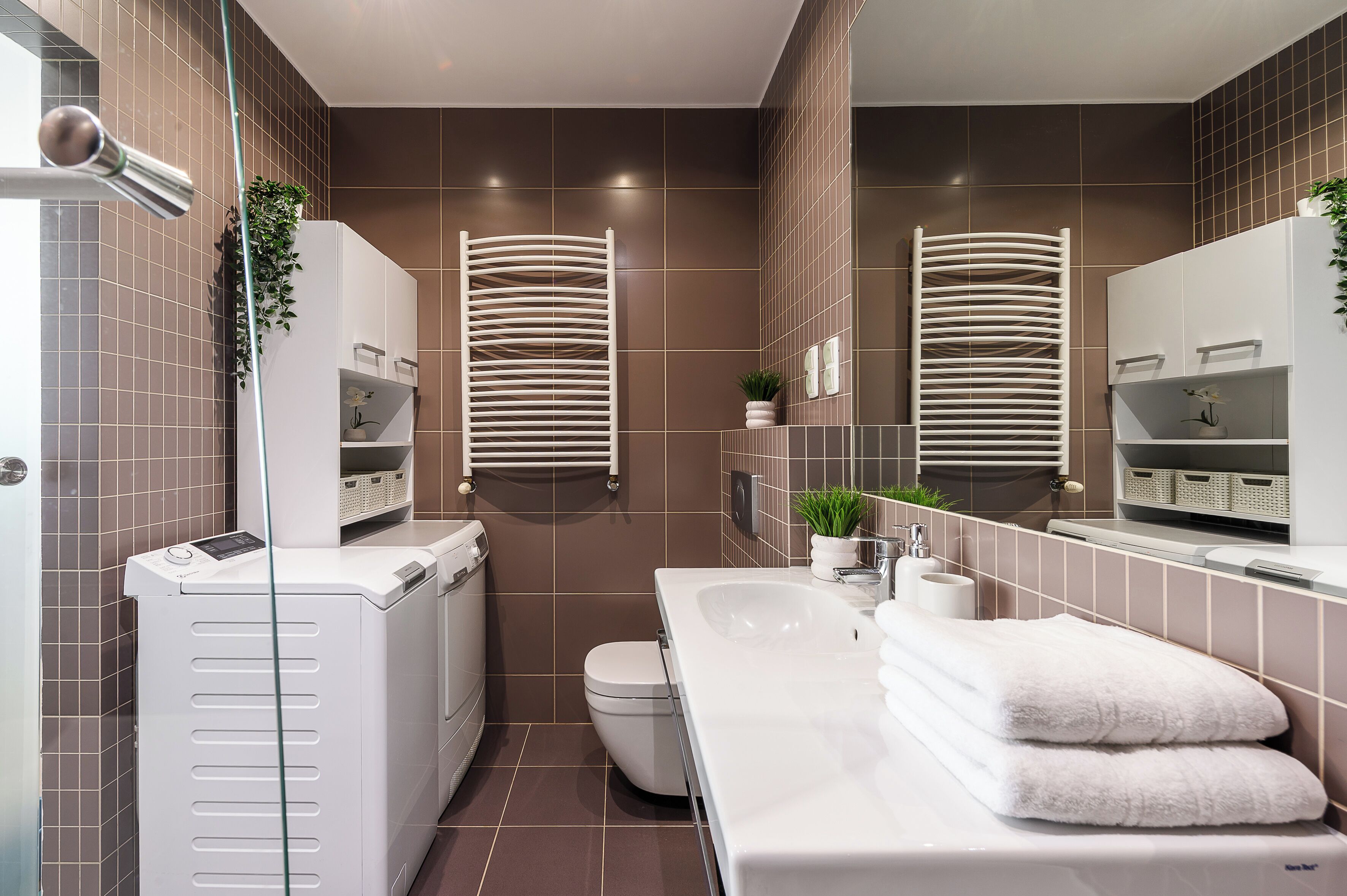 A modern bathroom with a white sink, toilet, and a glass shower enclosure.