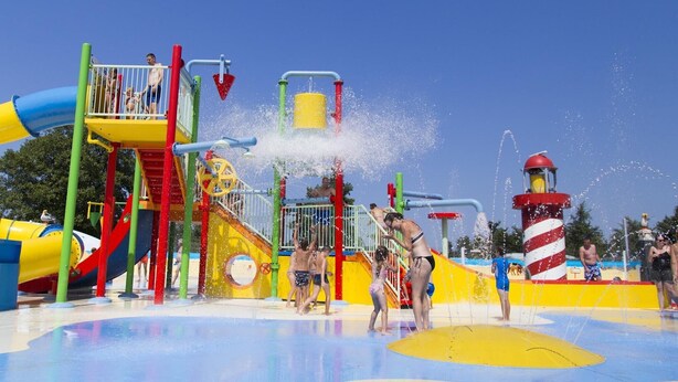 Un parque acuático con toboganes, chorros de agua y una estructura de juegos.