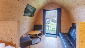 Un acogedor interior de cabaña con techo de madera, una mesa redonda, un sofá y una silla.