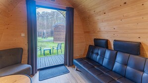 Interior de madera con sofá, un banco, una puerta que da al exterior y una pequeña mesa.
