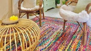 Une pièce chaleureuse, meublée de meubles en osier, agrémentée d’un tapis coloré et d’une petite table ronde décorée de bougies.