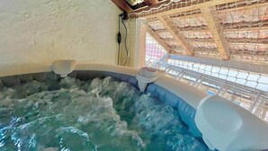Un bain à remous doté d’un plafond en bois et d’un écran en treillis métallique.
