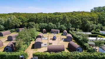 Een camping met meerdere koepelvormige accommodaties, een gemeenschappelijke ontmoetingsplaats en een bebost landschap.