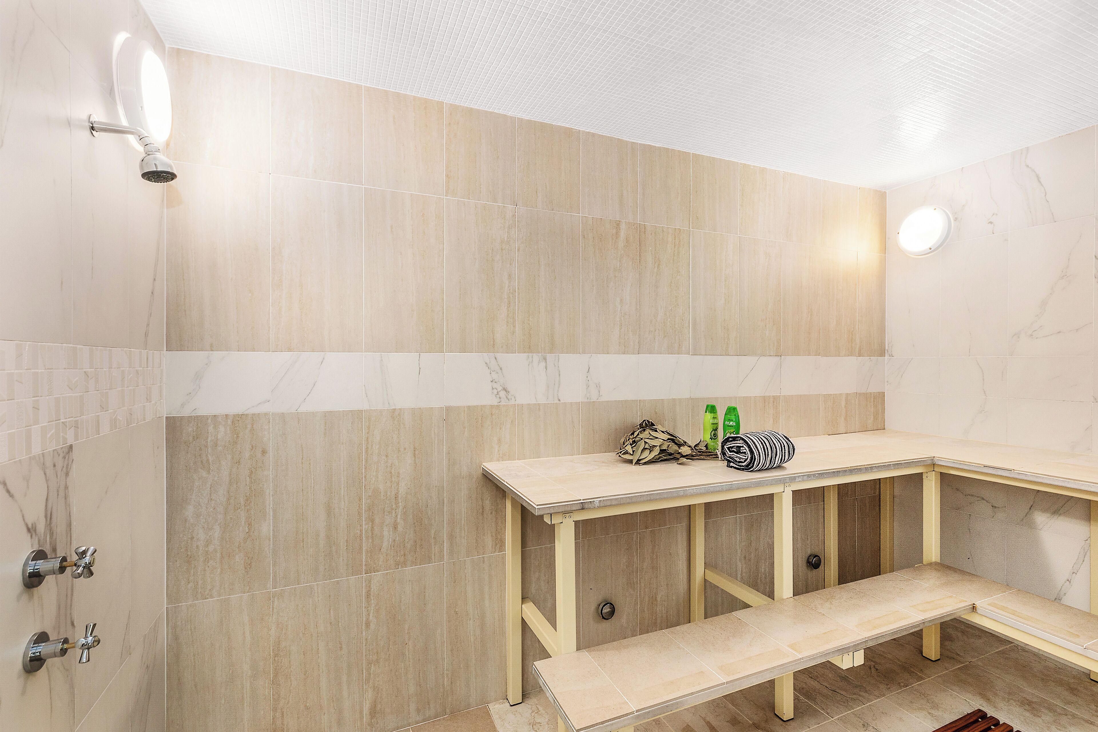 A bathroom with beige tiles, a wooden vanity, and a shower with a handheld showerhead.